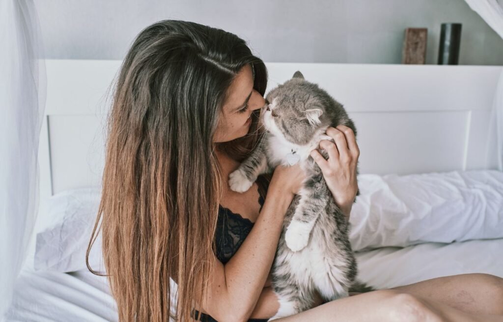 Why does my cat love me so much — woman holding and cuddling her cat on the bed